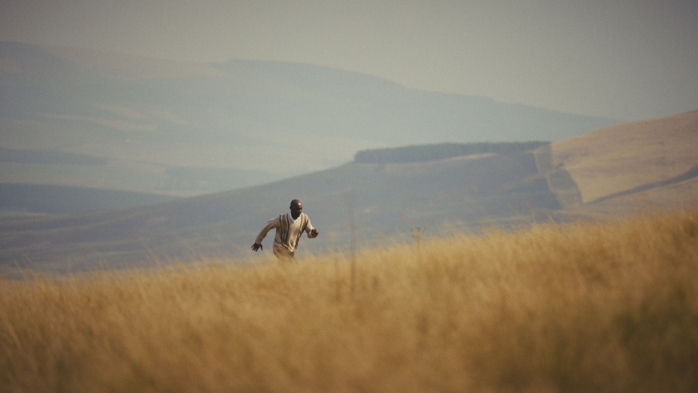 Jabulile Majola running through tall grass on a hillside